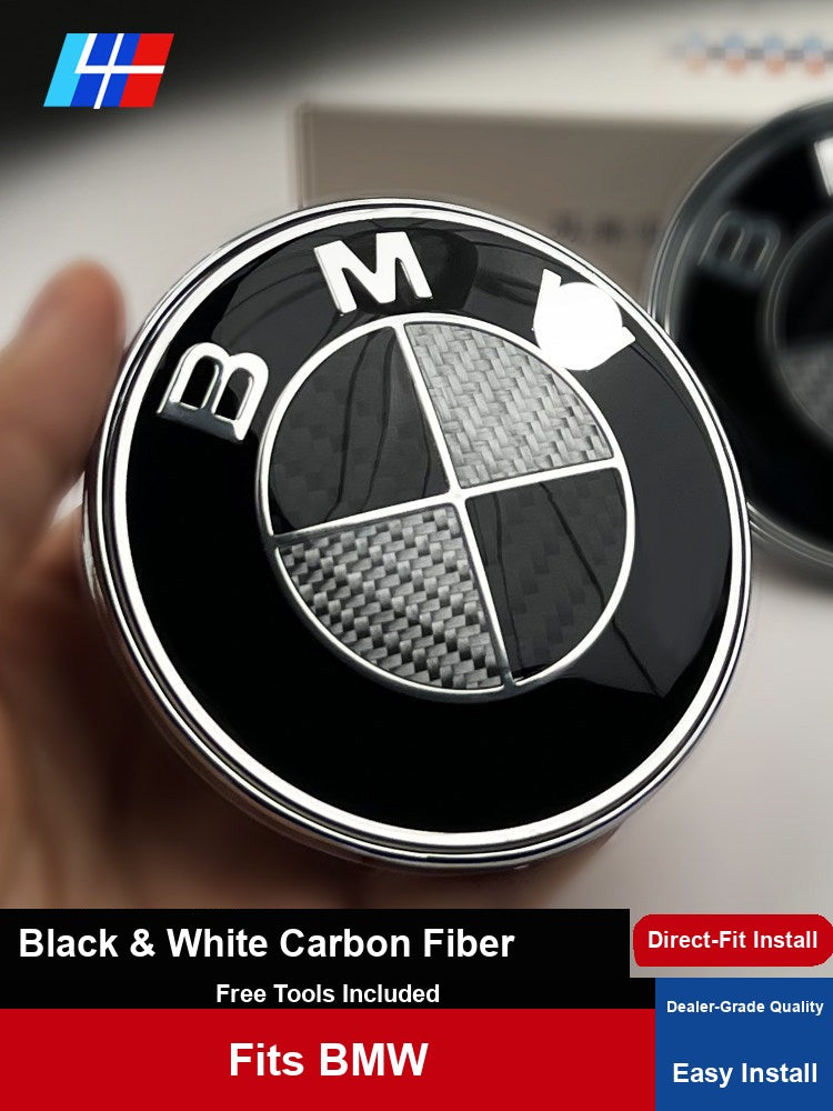 BMW black and white carbon fiber emblem badge held in hand, front hood view