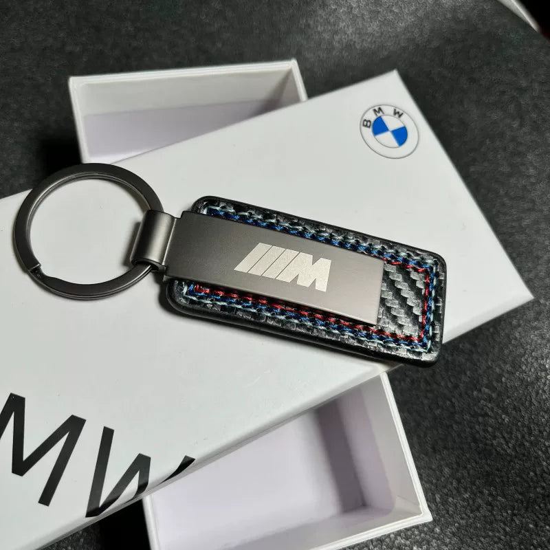 BMW M keychain close-up showing carbon fiber panel and tricolor stitching