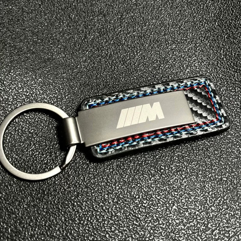 BMW M carbon fiber keychain on dark textured background