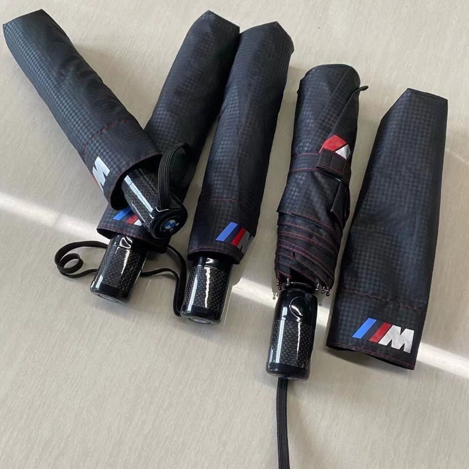 Four folded BMW M carbon fiber pattern umbrellas with wrist strap and carbon fiber handle