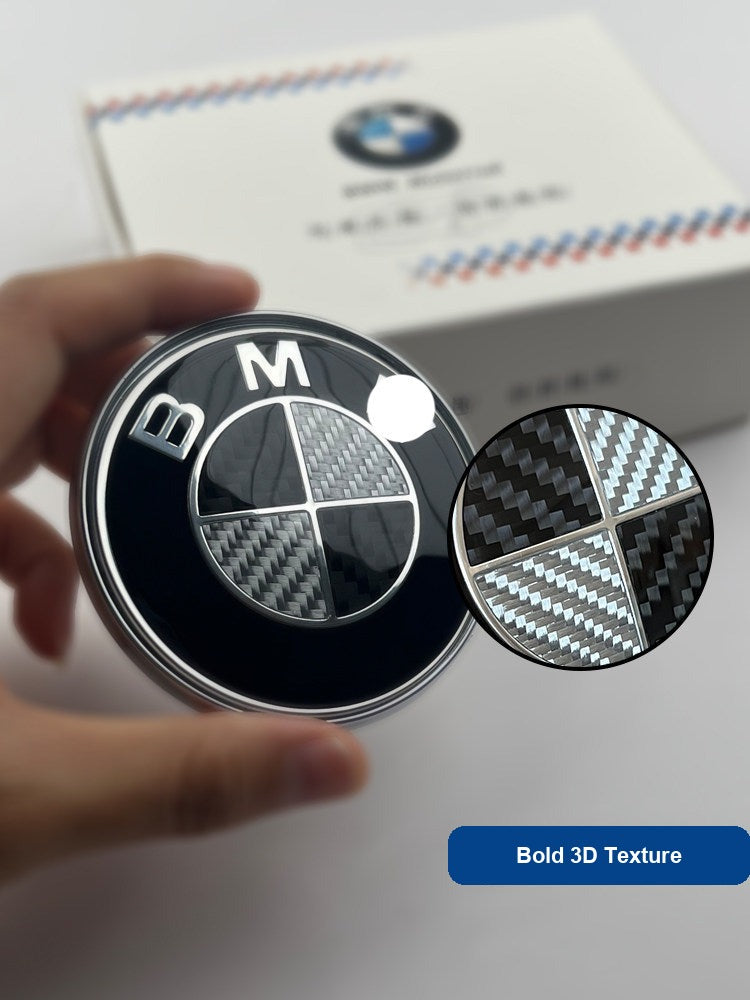 Close-up of BMW carbon fiber emblem badge showing carbon weave texture