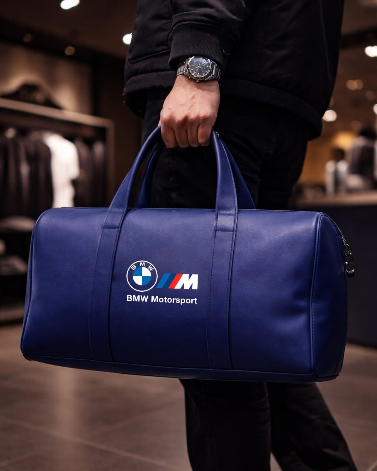 Man carrying BMW Motorsport navy blue leather duffel bag